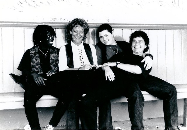 Blueshouse Black and white photo of band. Smiling. Lynne sat across the other three members laps.