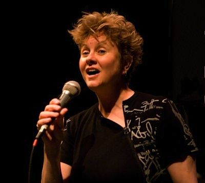 Julie McNamara photo Tony Fields Colour photograph of Julie McNamara singing or doing stand-up comedy, with microphone