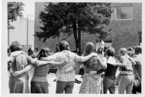 Women dancing in  huge circle as Susan sings and plays guitar