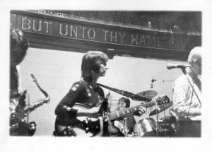 Black and white picture of saxophonist, guitarist, drama, singer, on stage.