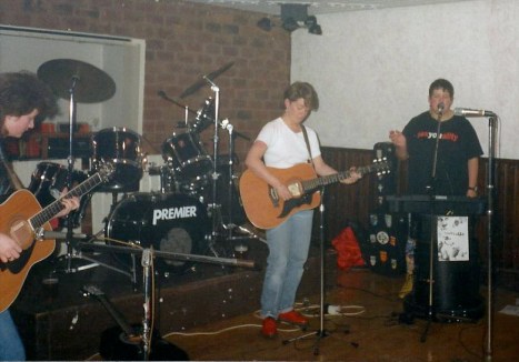 The four Fabulous Jam Tarts in concert. two guitarists at front of stage with clarinet player, drums behind.