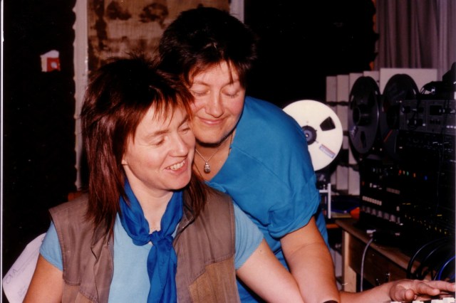 In the studio 1 Colour photo of Rosemary and Jana in the Ova music studio surrounded by equipment. Jana looks over Rosemary's shoulder and the two smile happily.