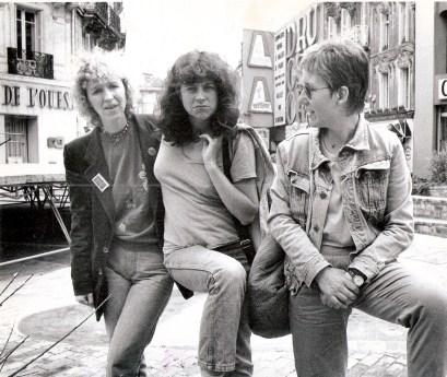 Black and white photo of Maggie Nicols, Lindsay Cooper, Irene Schweizer (head tilted to look at Maggie and Lindsay). A background of French city streets.