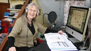 Colour image of Maria recording music using a computer. Big smile.