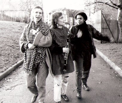 The three members of No Rules OK in a black and white shot, walking along a fortpath talking animatedly and smiling. Shirli holds a clarinet.