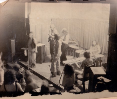 A tattered photo of the band on stage at the Edinburgh conference taken from above shows them all playing and some of the audience watching and dancing.
