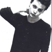 Pauline Channing in black tee shirt, hand behind head, looking thoughtful.