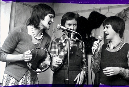 Three singers using microphones focusing carefully on each other during rehearsal.