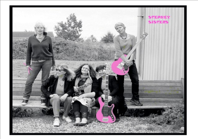 Cover of the CD is a black and white photo of the women from the Stepney Sisters, with bass, drumsticks and guitar and their name picked out in bright pink. The 5 women and their instruments are sitting or standing on a wooden bench in an outdoor location, trees and a barn in the background.