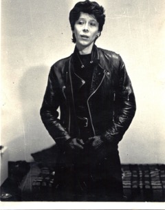 Nina Rapi, black and white photo, in black leather jacket looking serious.