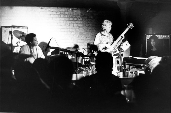 Terri Quaye playing congas, with bass player and keyboards on stage.