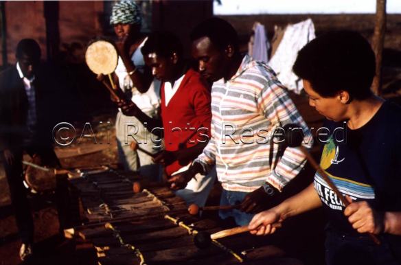 Terry Quaye playing balafon, African xylophone, outdoors with other musicians in Zimbabwe.