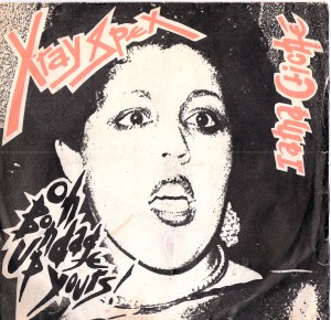 cover of Xray Spex record shows Poly Styrene's face while singing, and titles of songs 'Oh bondage, up yours' and 'I am a cliche.'
