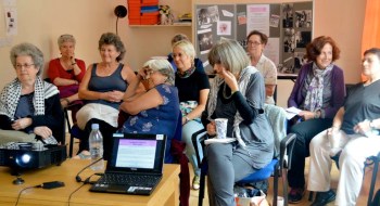 A group of women enjoying a workshop discussion; display board of WLMA items in background.